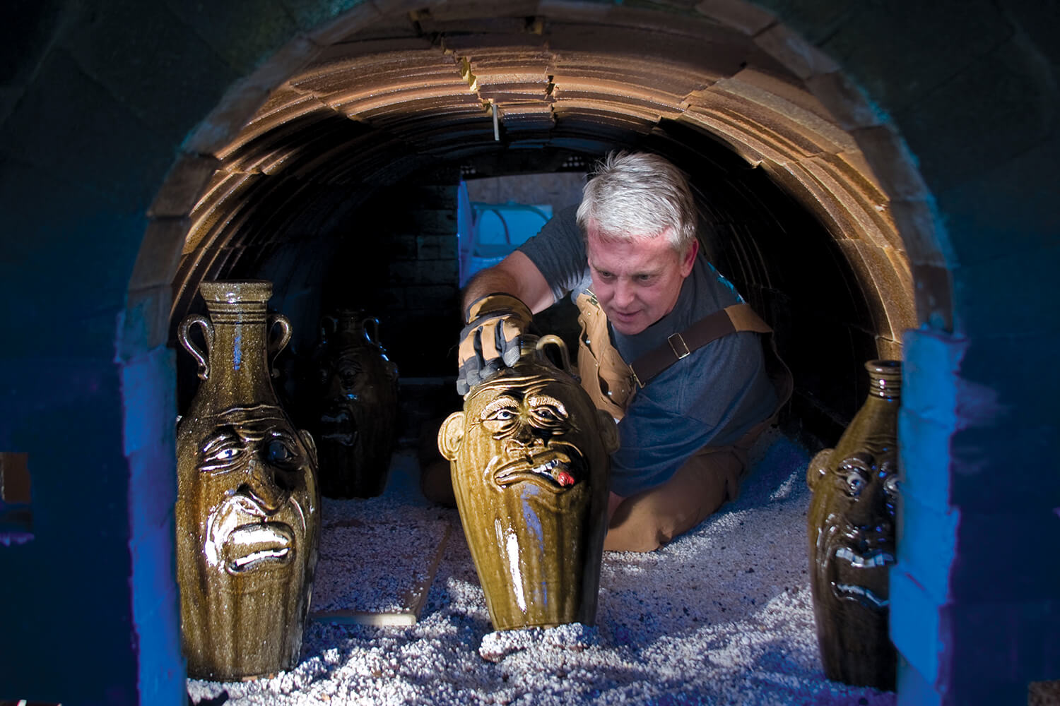 Potter Jeff Young retrieves finished pieces from his kiln in Vale, where he crafts jug faces.