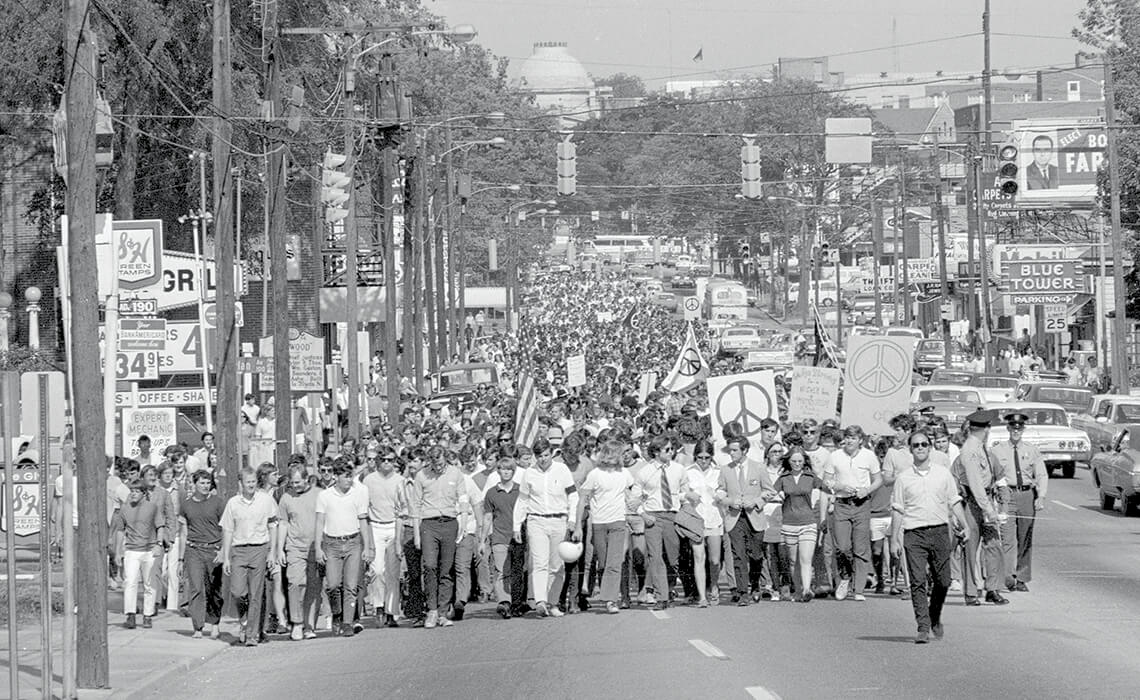 Students, with peace signs and flags, marching to the State Capitol in the streets.