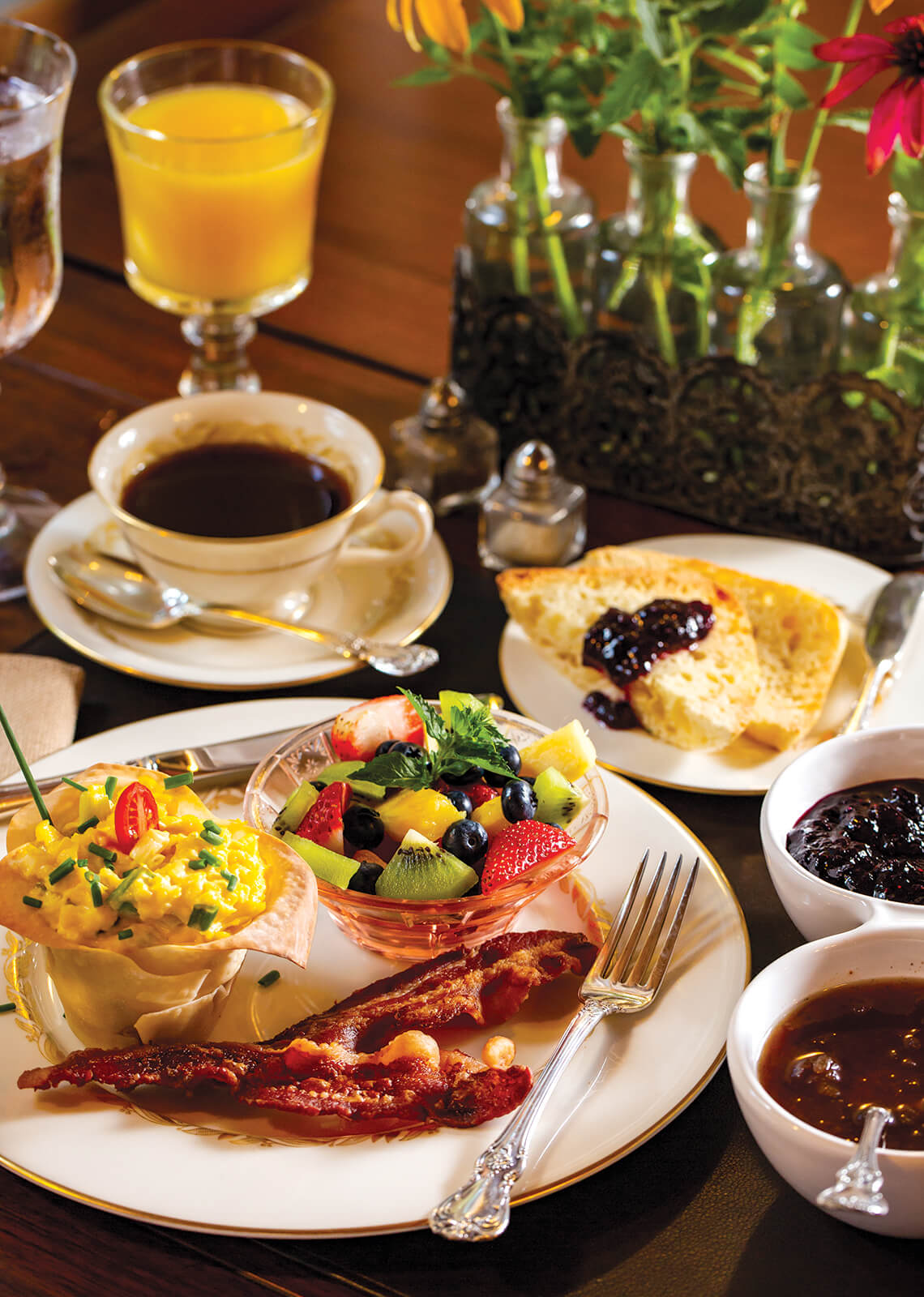 An elaborate breakfast meal with eggs, bacon and fruit.