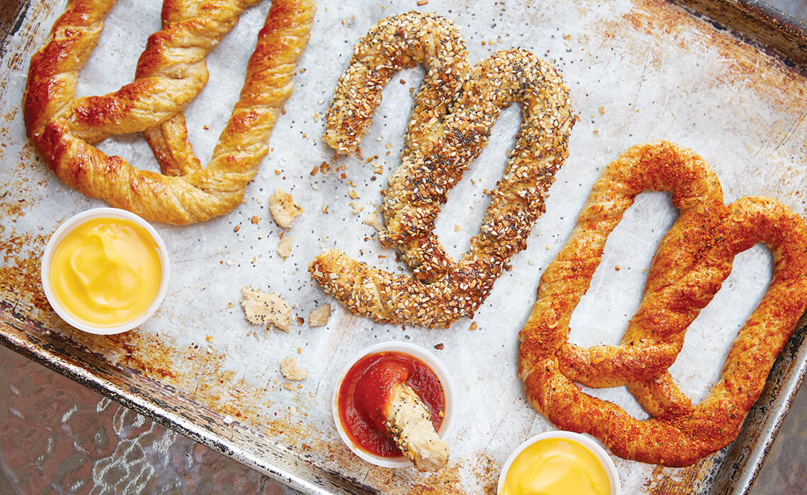 Three different flavored pretzels with assorted dipping sauces.