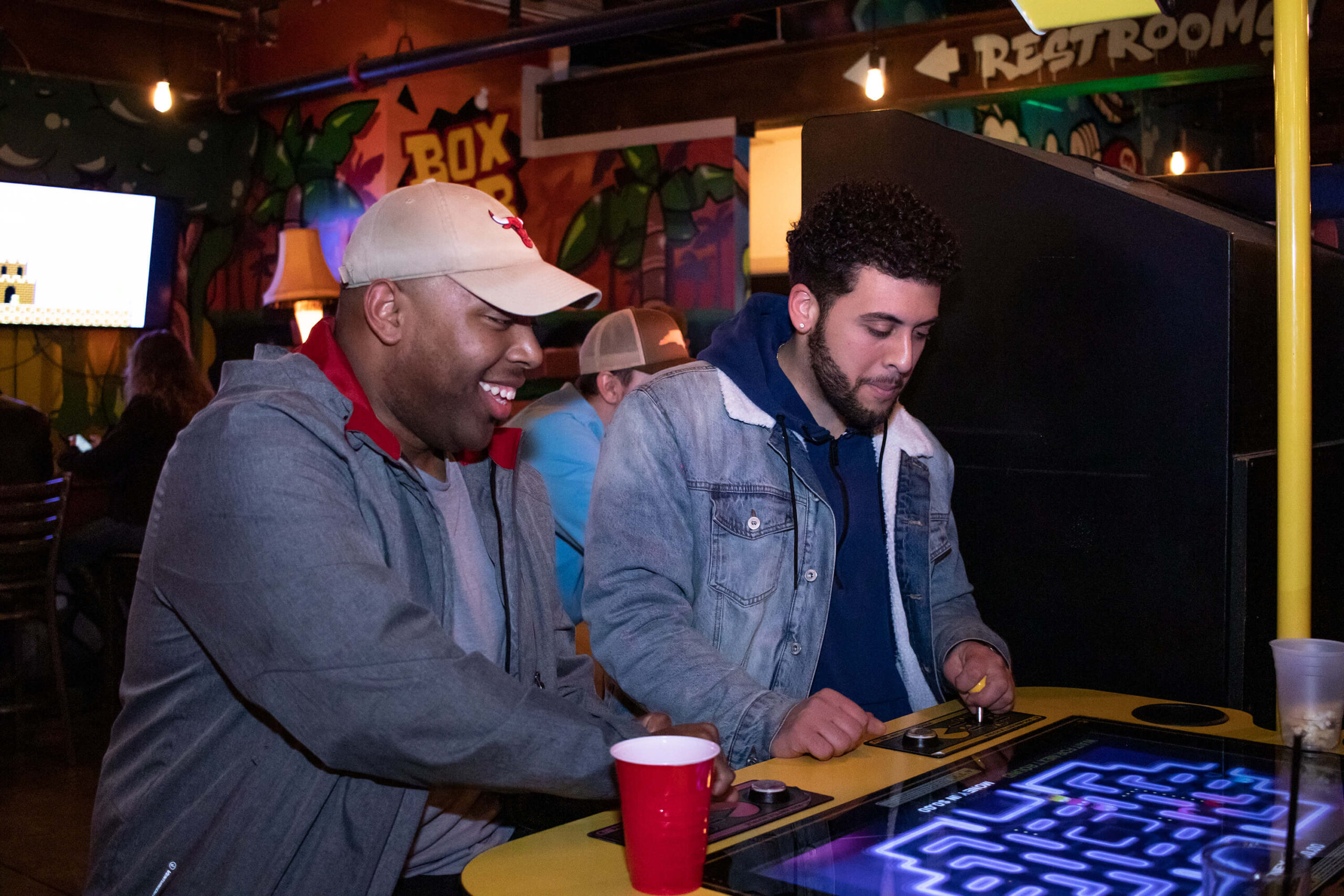 Two people playing PacMan at the Boxcar Bar + Arcade