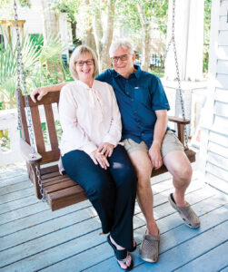 Debbie & Ricky Evans sit on swinging chair of porch.