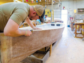 Student uses planer to shape boat trim.