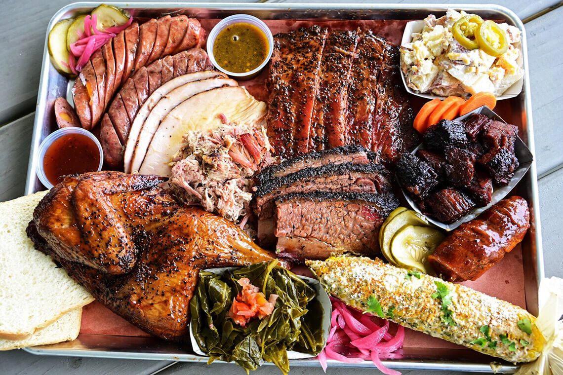 Platter of brisket, smoked chicken, sausages, and sides from Old Colony Smokehouse
