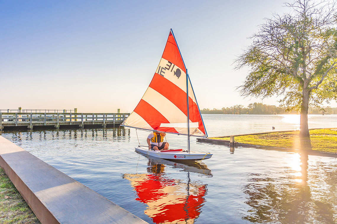 Person pilots a sunfish boat along the waterfront in Edenton, NC
