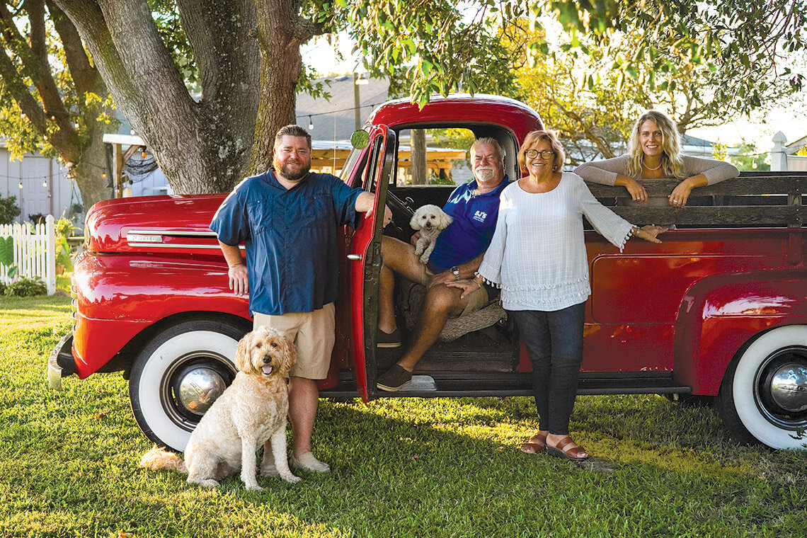 The Beasley family poses around a red pick-up truck.