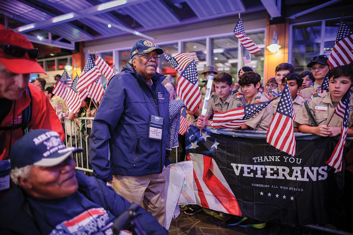 Former servicemember Garland Wallace walks past a cheering Boy Scout Troop at PTI Airport