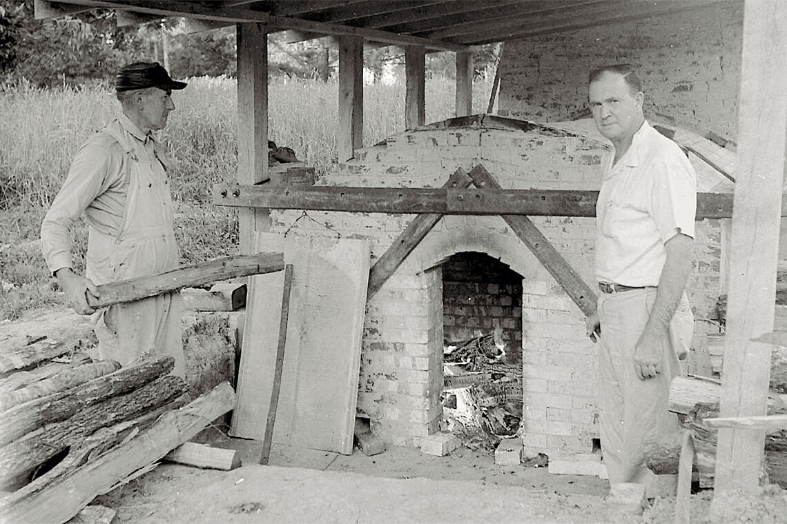 Ben Owen Sr. stands at a kiln, symbolizing the beginning of the Seagrove pottery legacy.