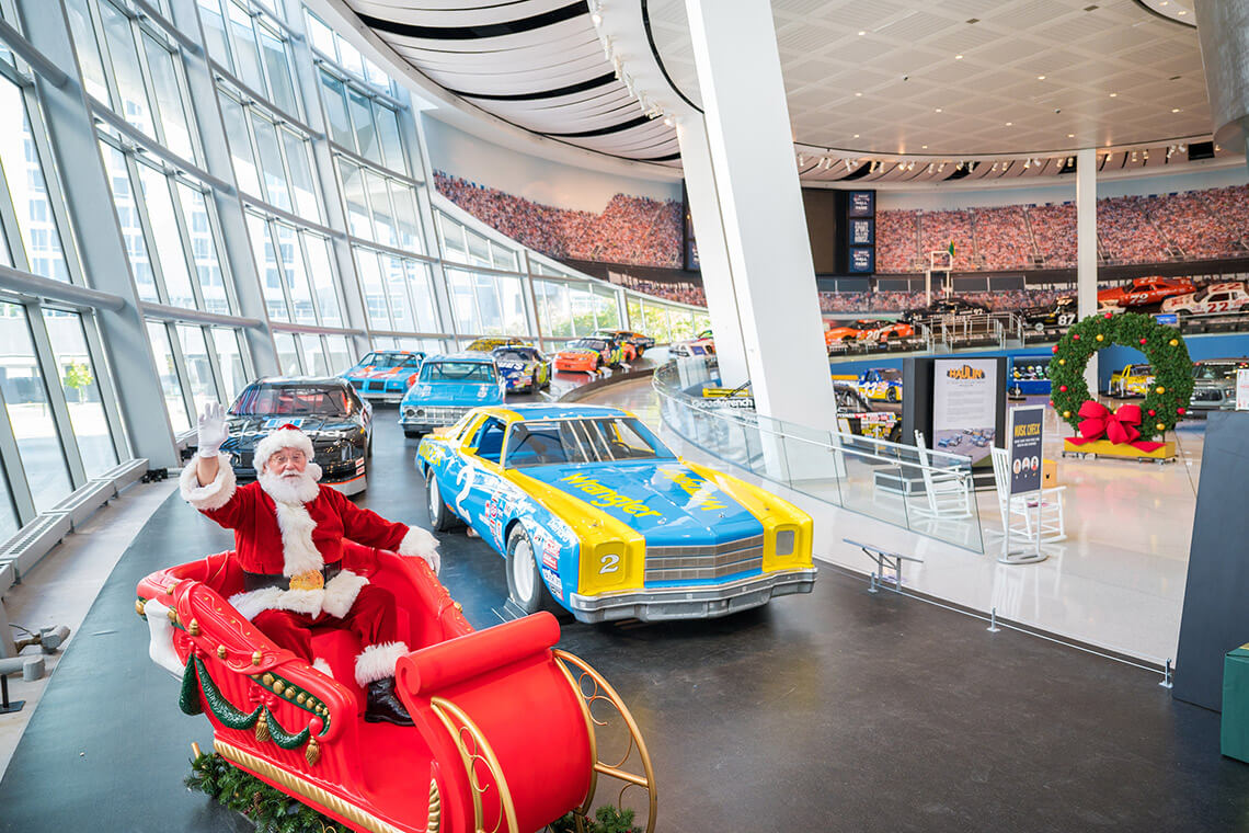 Santa in sleigh next to race cars at the NASCAR Hall of Fame