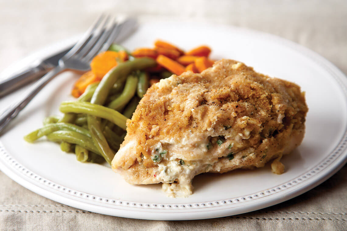 Plate of smothered chicken breast with green beans and carrots