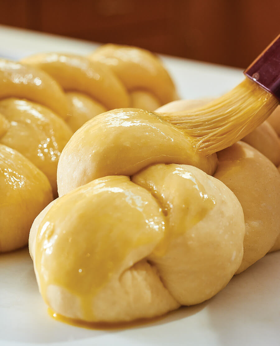 Brushing unbaked challah bread with egg wash