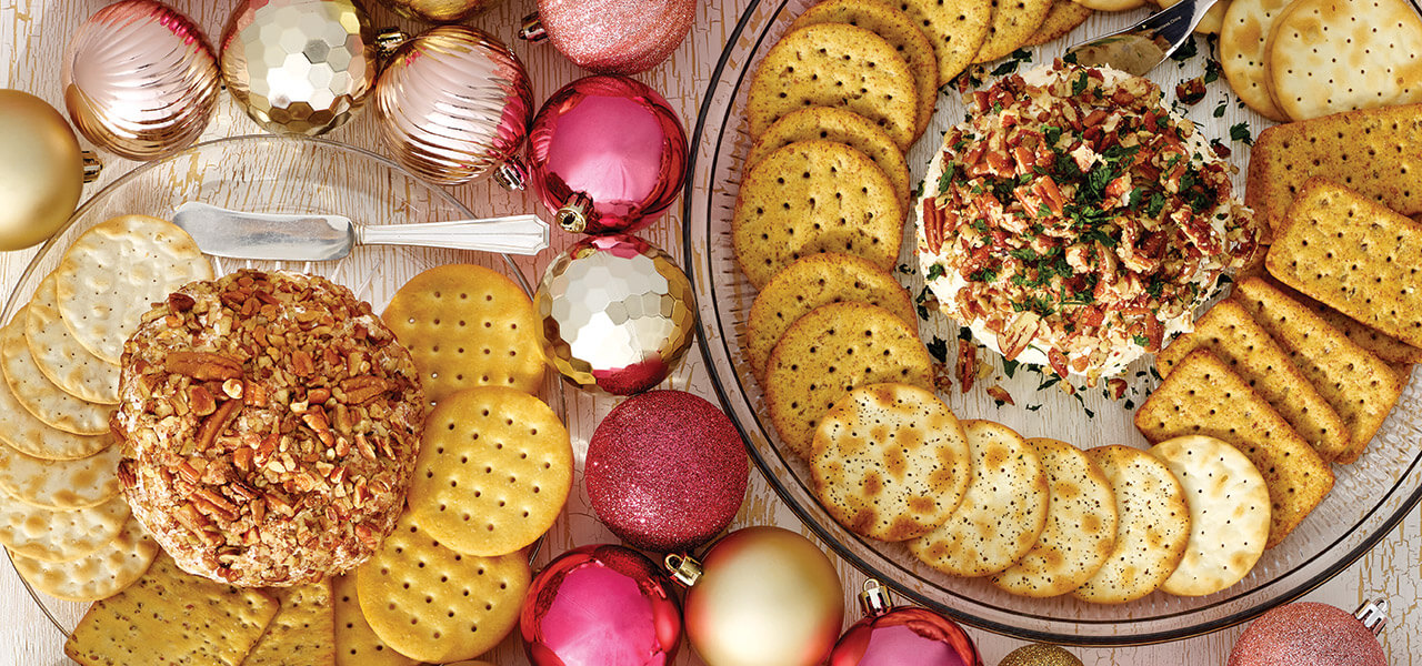 Table with 2 cheese balls surrounded with crackers and ornaments.