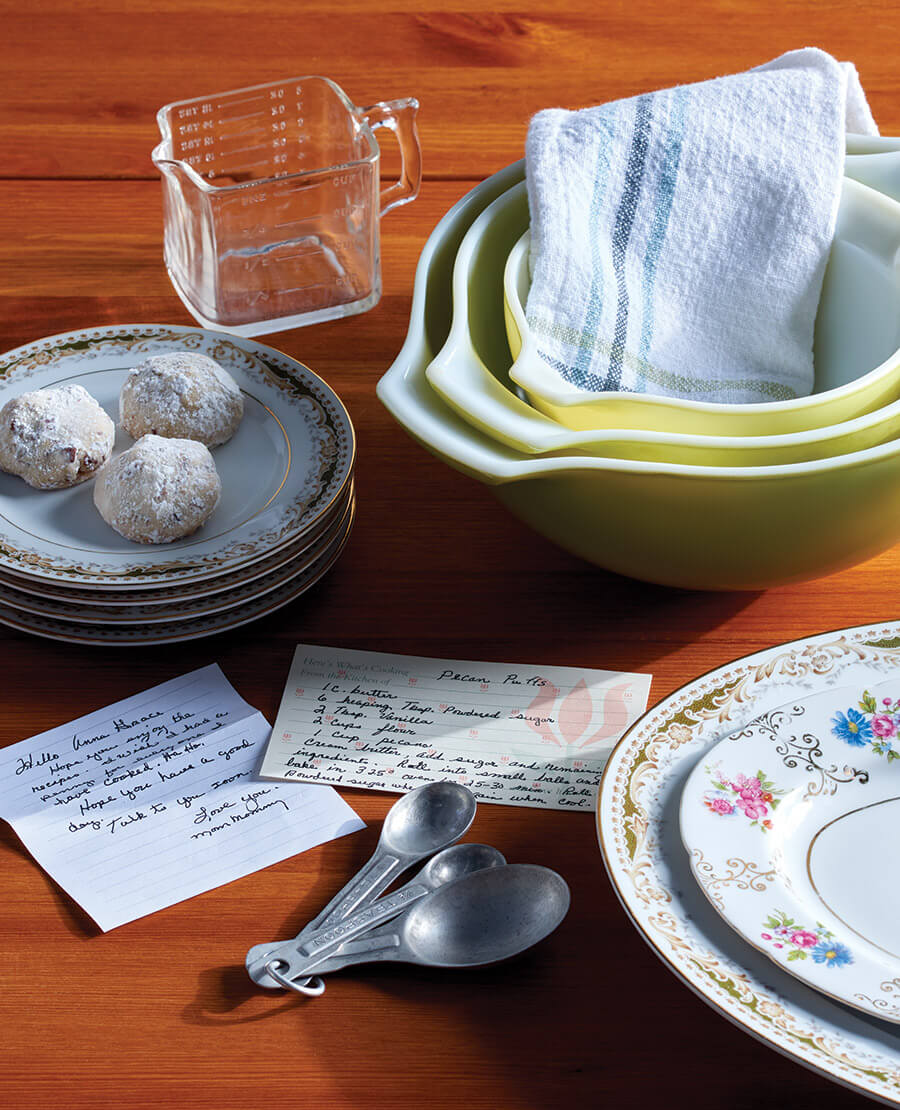 Mixing bowls and measuring spoons along with the handwritten recipe for pecan puffs