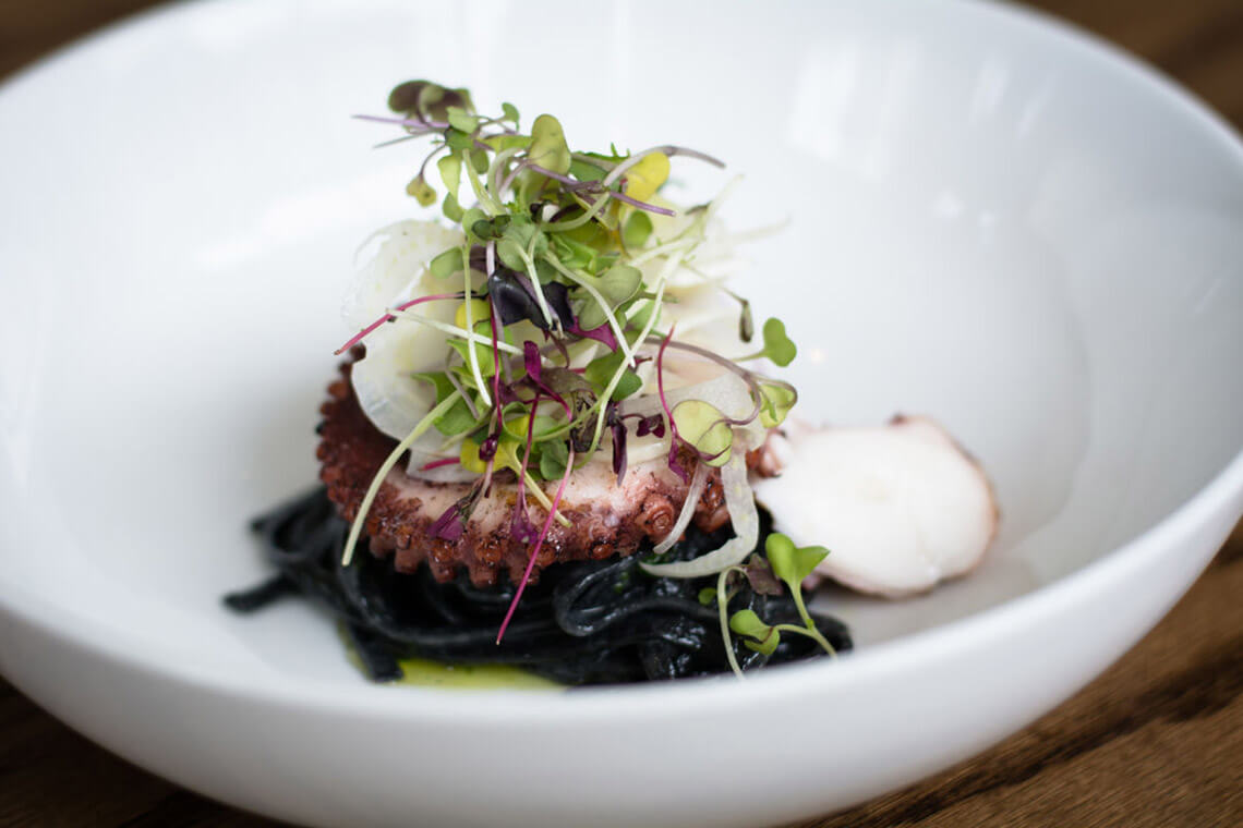 Plate of squid topped with micro greens at ORO Restaurant & Lounge