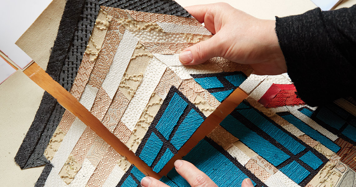 Caitlin Cary arranges needleprint pieces into a piece of art.