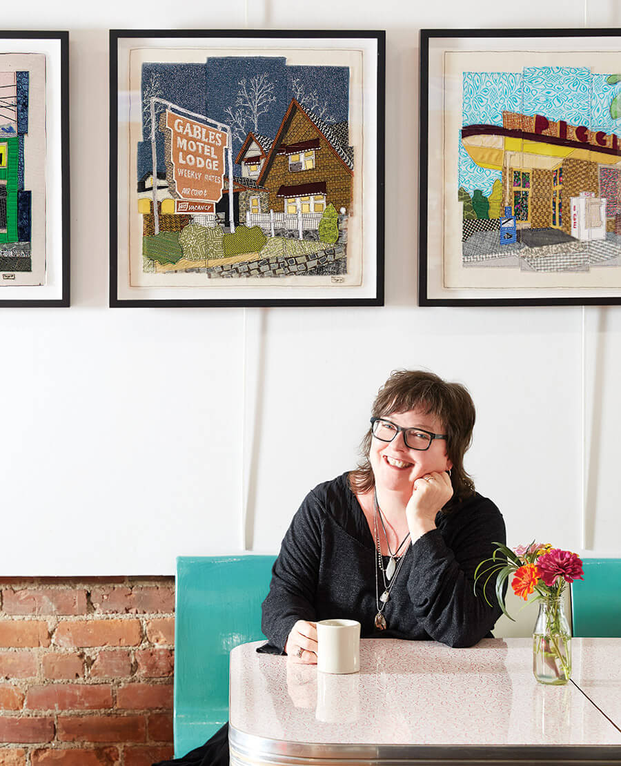 Caitlin Cary sits in front of needle prints of iconic buildings around downtown Raleigh.
