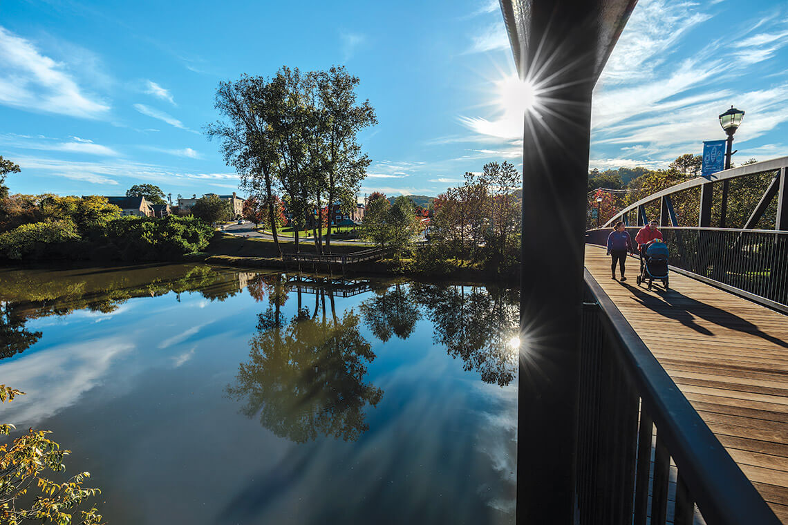 People cross footbridge over South Fork Catawba River