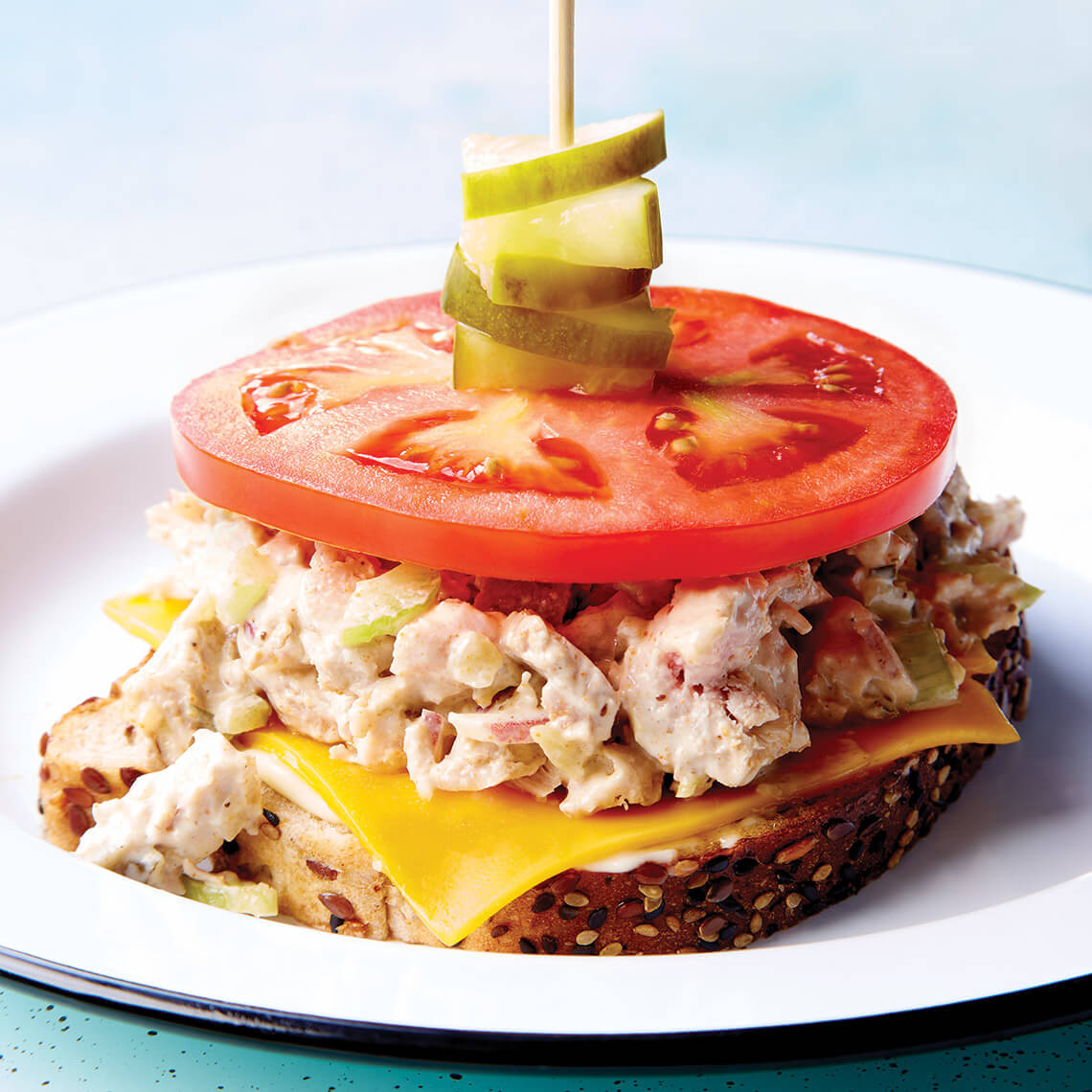 Open-faced tuna melt topped with tomato and pickles