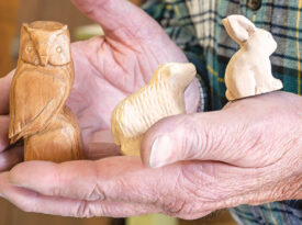 Rick Carter holds tiny wooden animal figurines, a connection to the early work of the original Brasstown Carvers
