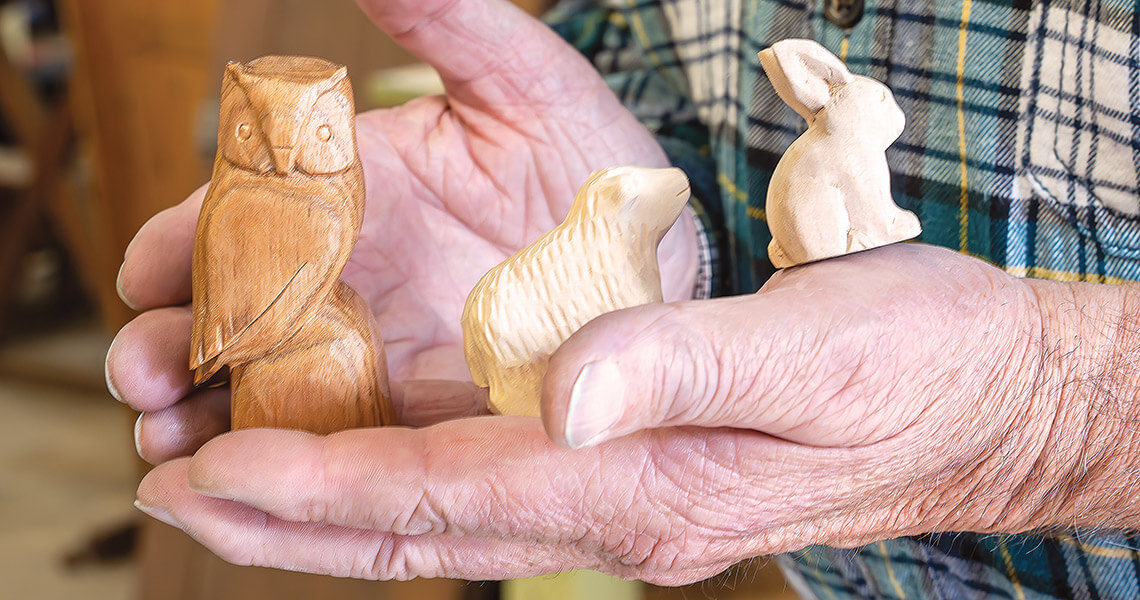 Rick Carter holds tiny wooden animal figurines, a connection to the early work of the original Brasstown Carvers