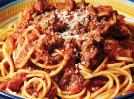 bowl of spaghetti topped with sauce.