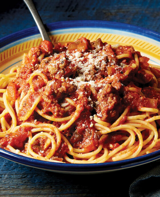 bowl of spaghetti topped with sauce.