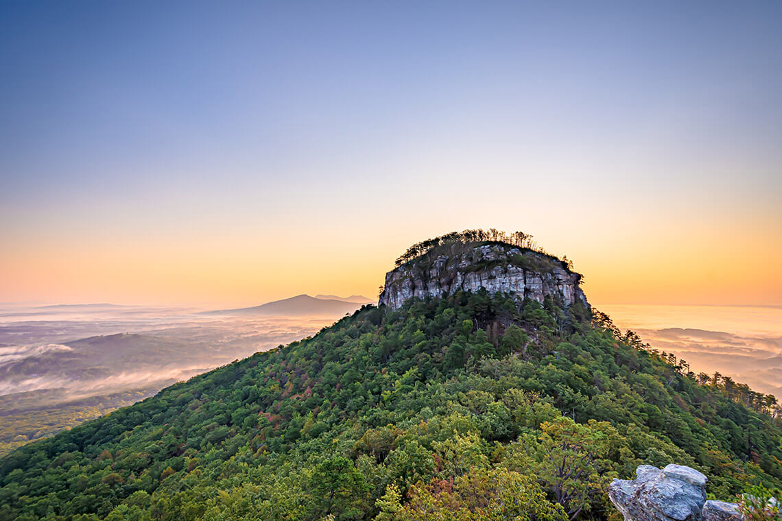 Pilot Mountain rising high, with the Blue Ridge Mountains in the background.