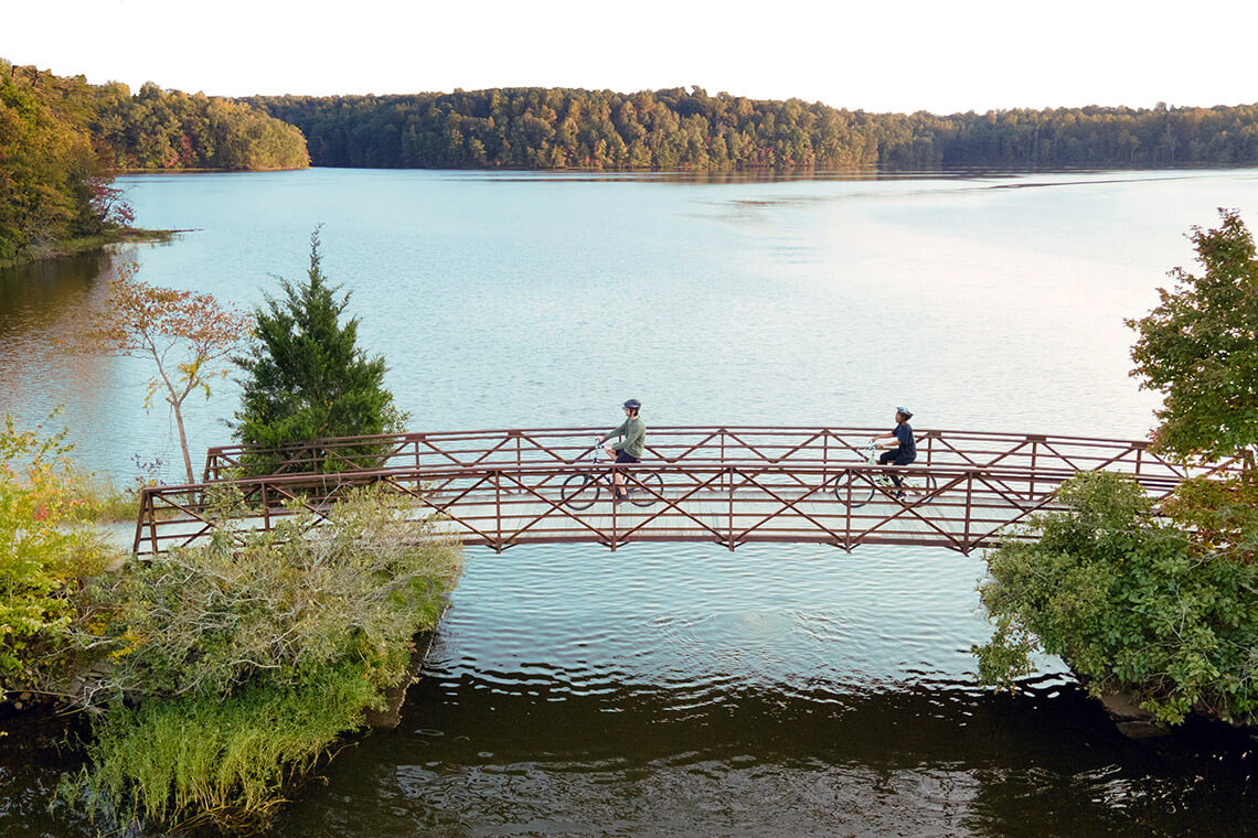 People cycle across the foot bridge at Salem Lake Trail