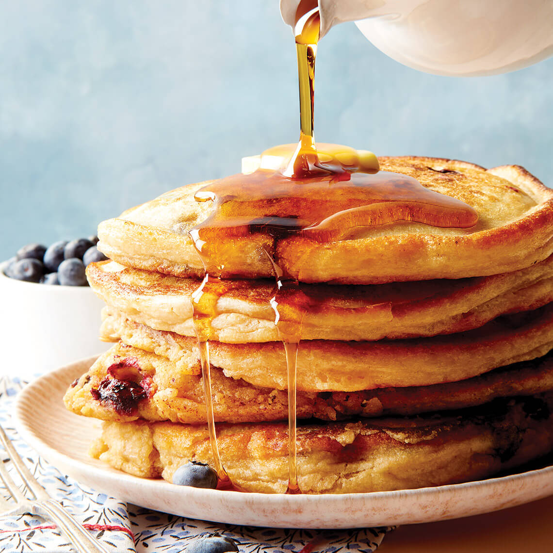 Pouring syrup over blueberry buckwheat pancakes