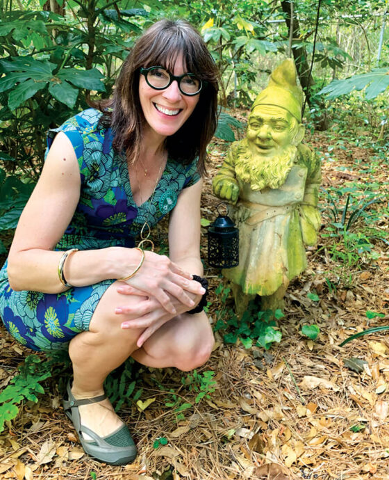 Elizabeth Hudson with a gnome in Elizabethan Gardens.