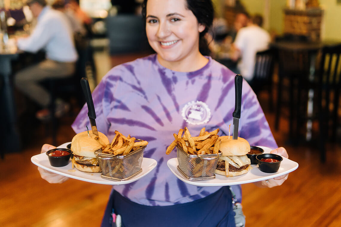 Waitstaff holds burgers at Me's Burgers & Brews