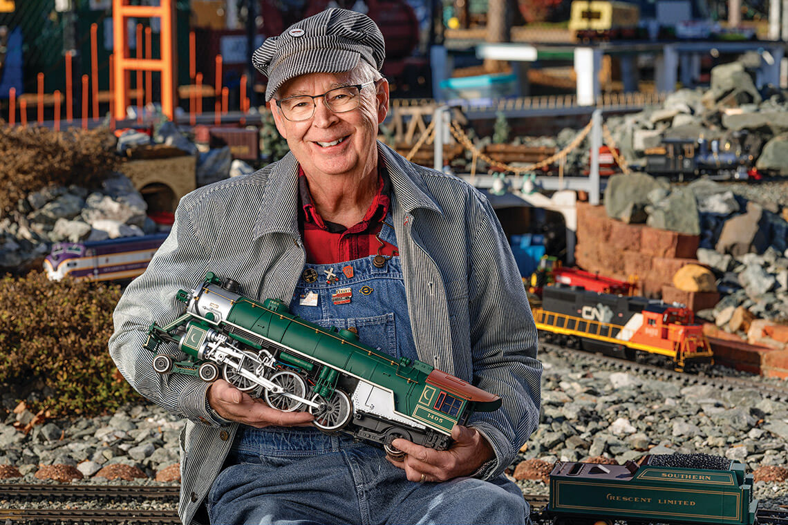 Neil Bromilow shows off a reproduction of a 4-6-2 “Pacific” locomotive in front of the Gibsonville Garden Railroad