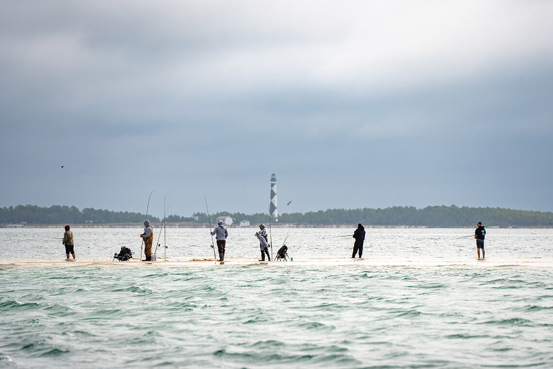 North Carolina fishing folks weather the waves as the tide rises over the sandbars at Cape Lookout.
