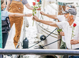 Barry Keyes and Dan Smith hand roses to visitors when they arrive in Elizabeth City.