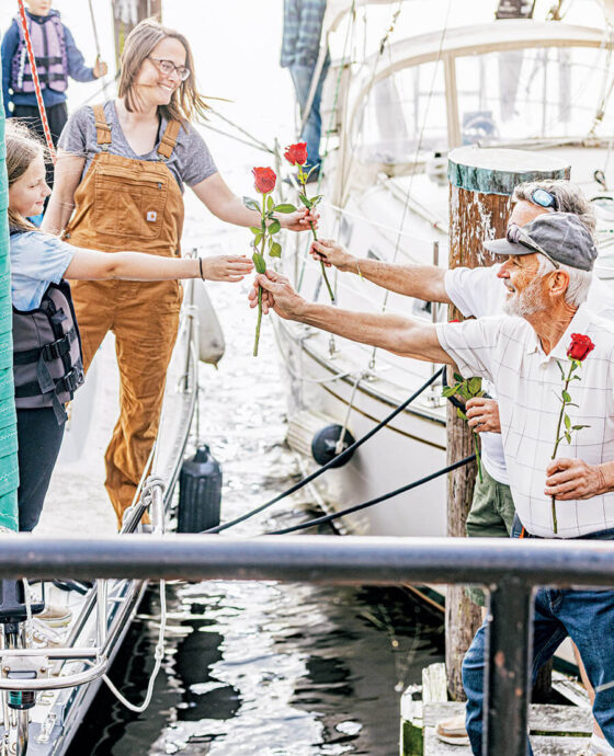 Barry Keyes and Dan Smith hand roses to visitors when they arrive in Elizabeth City.