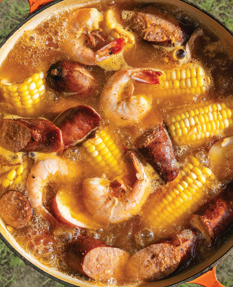 Shrimp boil with corn, sausage, and potatoes boiling in a pot