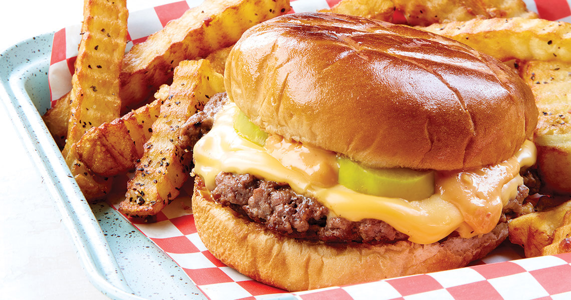 Smash cheeseburgers and pepper crinkle cut fries on a tray