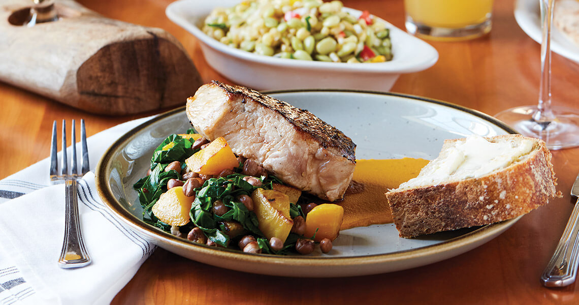 Grilled pork chop, succotash in the background at The Herringbone on the Waterfront