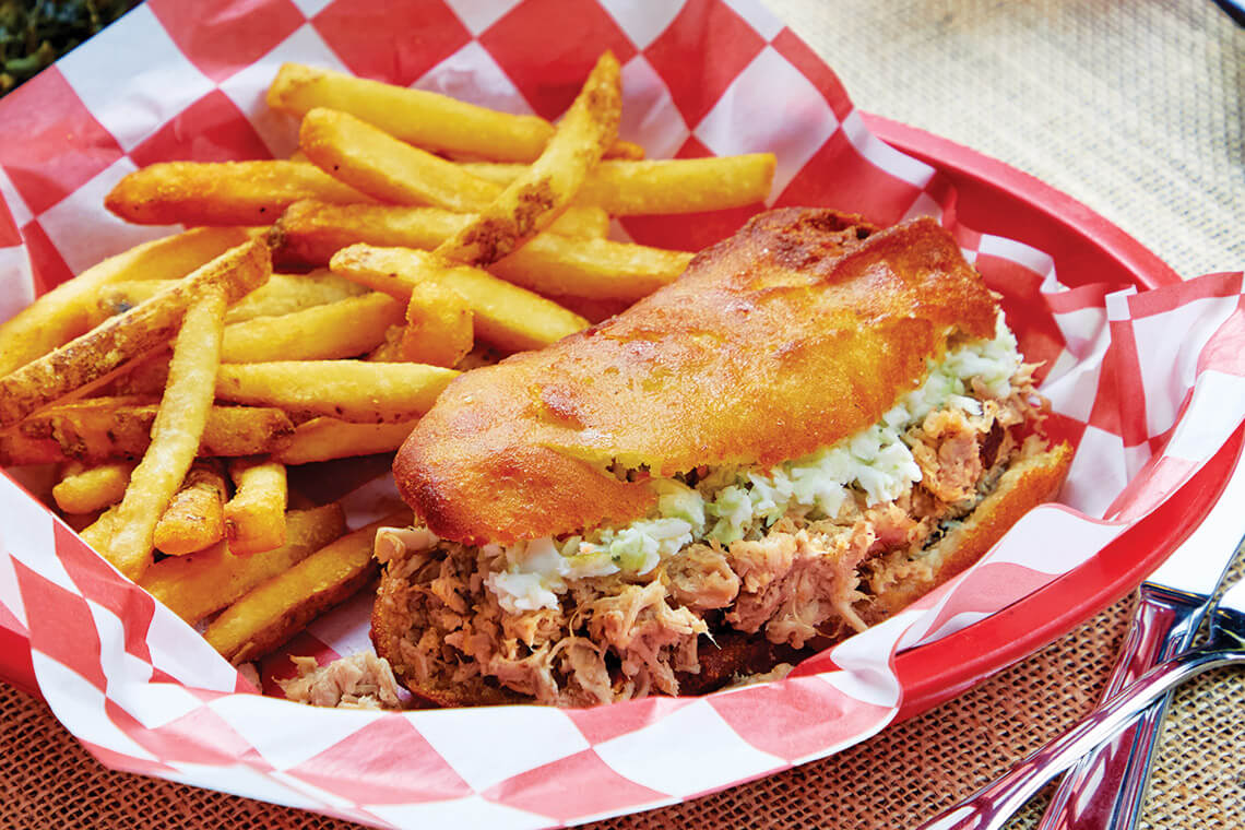 Kings Restaurant’s specialty creation, a hush puppy “bun” barbecue sandwich in a basket with fries