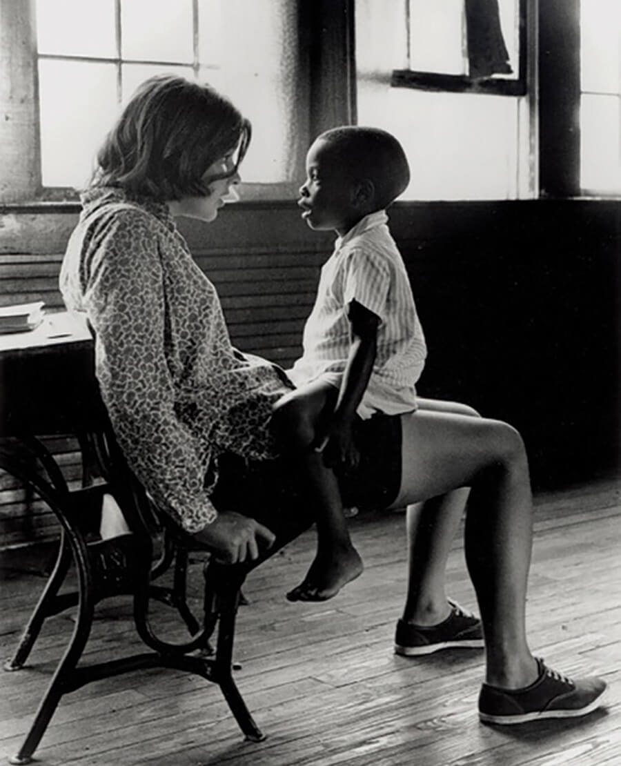 Photograph by Bruce Roberts of teacher comforting a Black student in a schoolhouse near Rockingham during de-segregation.