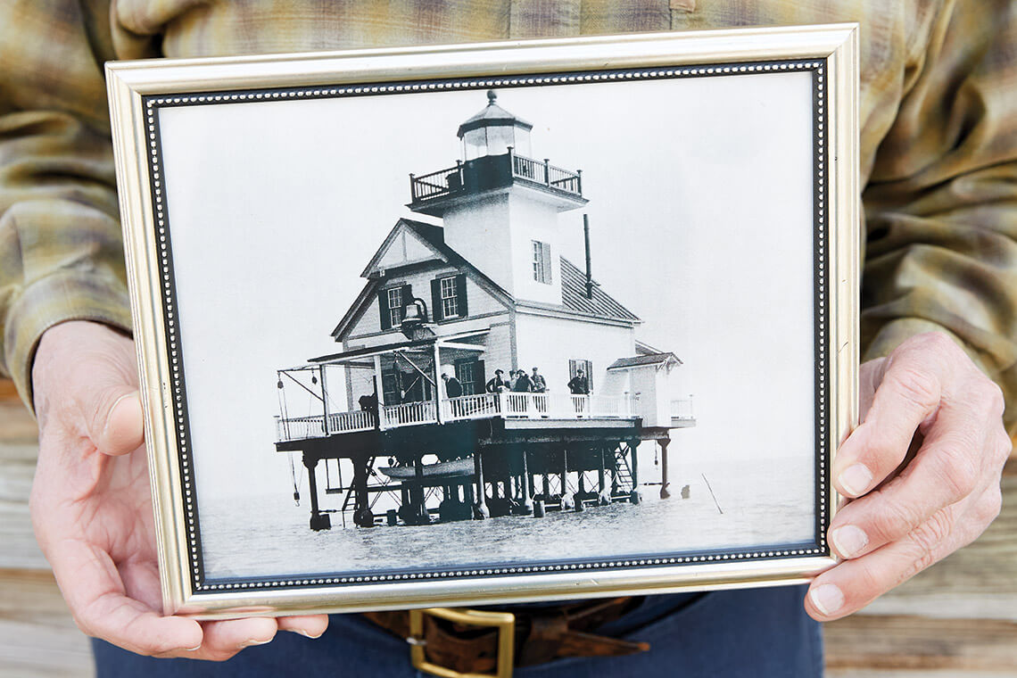 Phillips holds framed photo of the Roanoke River Lighthouse