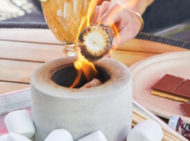 Hand toasting a marshmallow at Amante Tacos & Spirits