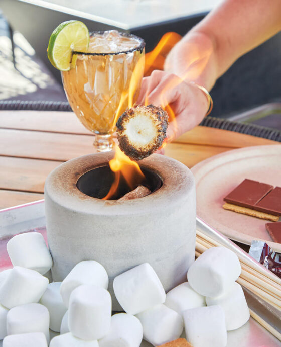 Hand toasting a marshmallow at Amante Tacos & Spirits