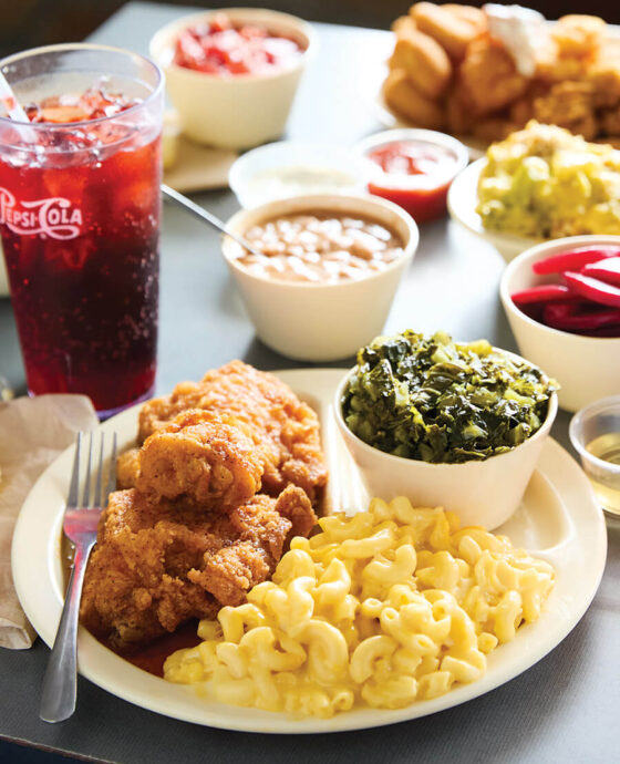 A spread from Southern Lunch in Lexington, including fried chicken, mac n cheese, collard greens, and a Pepsi