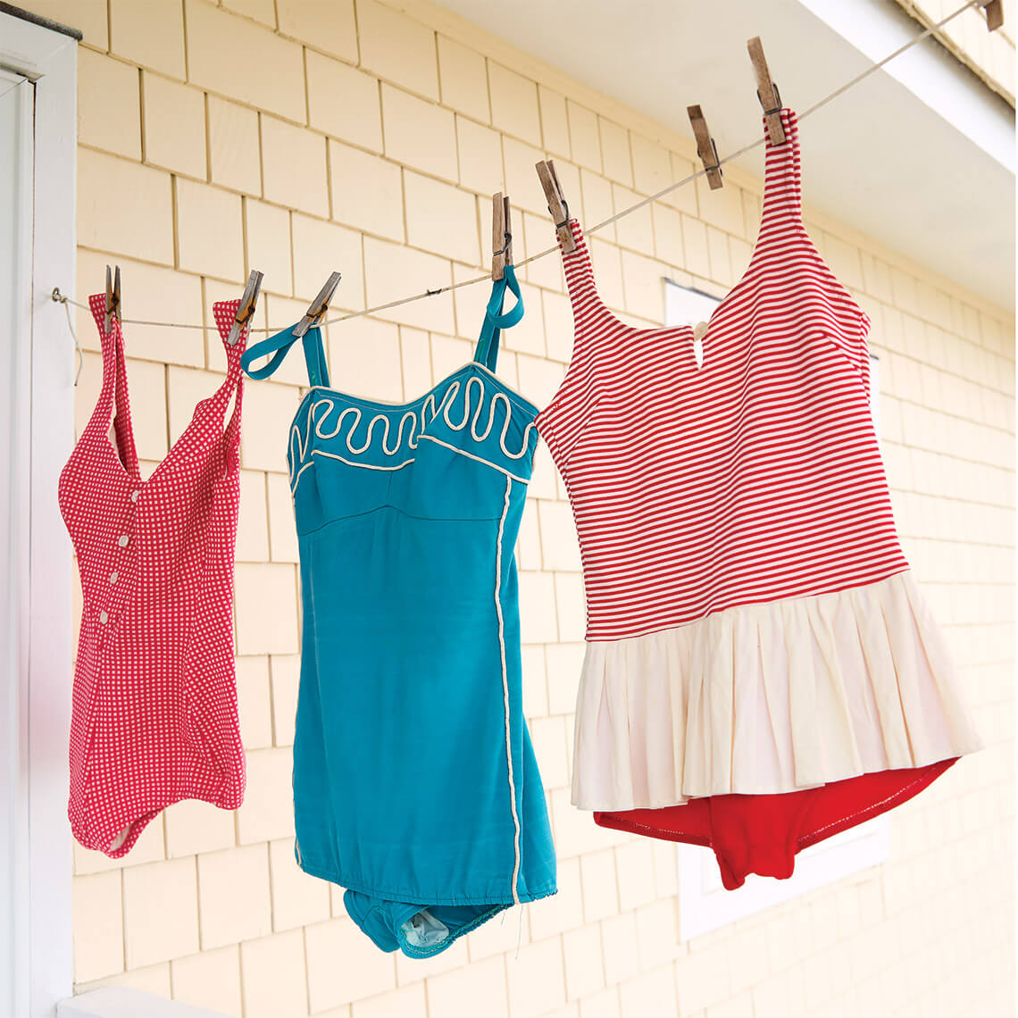 Three vintage bathing suits hang on the clothes line
