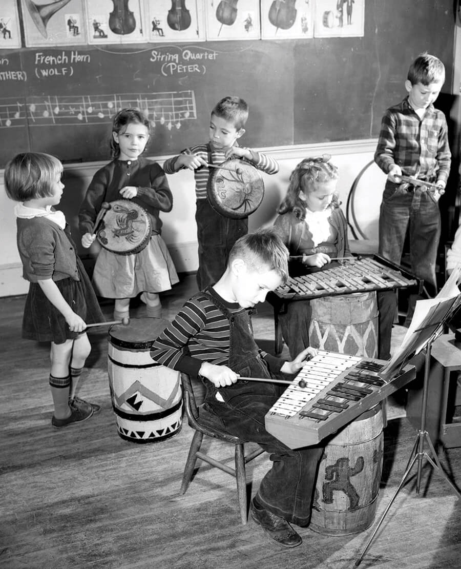 Students in a grade-school classroom play with child-size instruments in anticipation of the NC Symphony