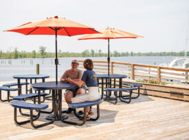 People sit at picnic tables at the waterfront in Columbia