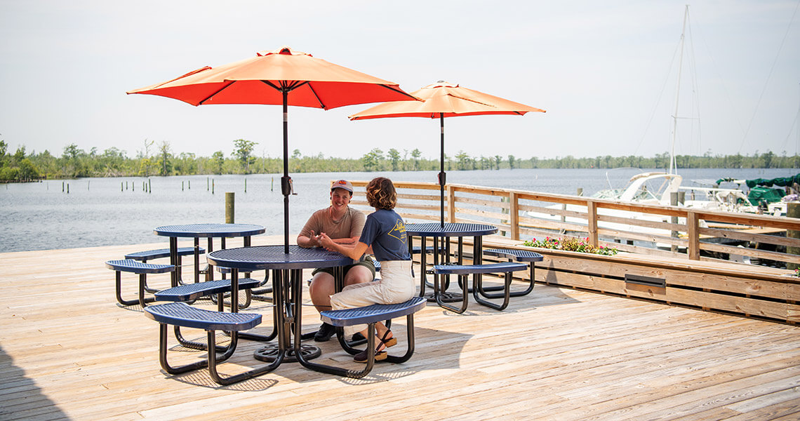 People sit at picnic tables at the waterfront in Columbia