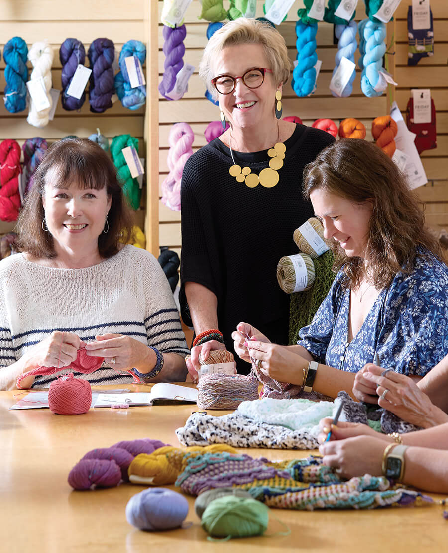 Former owner Holly Floyd at Bella Filati with knitters and crocheters working on their fiber projects.