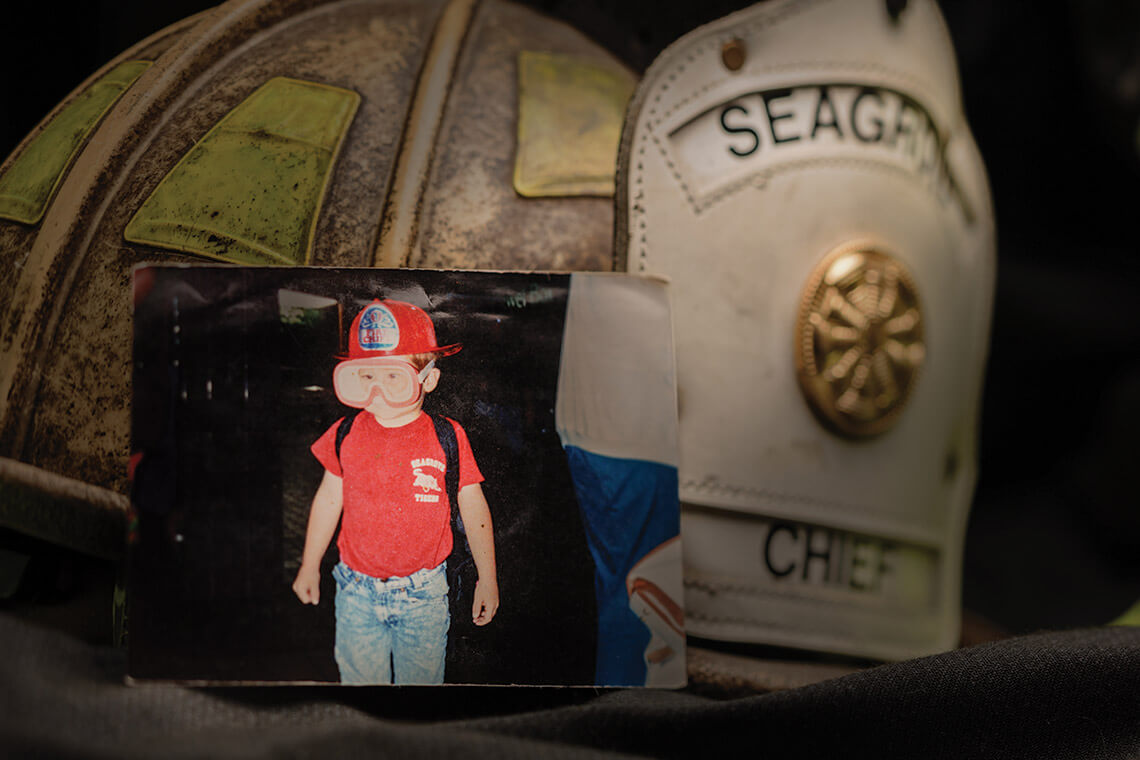 Young Dustin as a child dressed up in a firefighter's hat and protective glasses